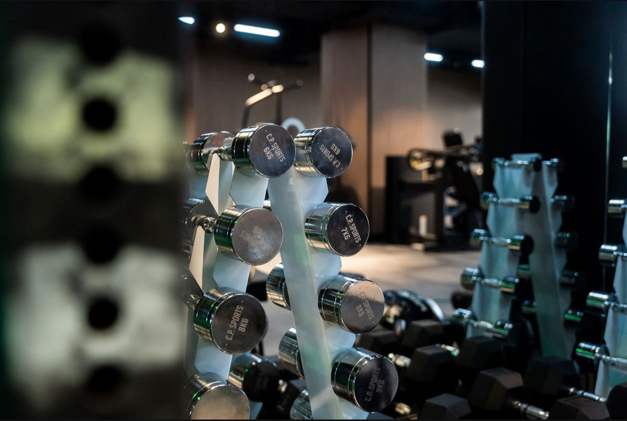 Freihanteln auf einem Regal im Fitnessstudio mit verschwommenen Details im Hintergrund.