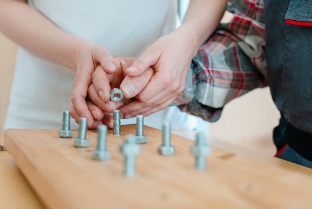 Nahaufnahme eines Mannes in der Beschäftigungstherapie, der eine Mutter auf eine Schraube schraubt