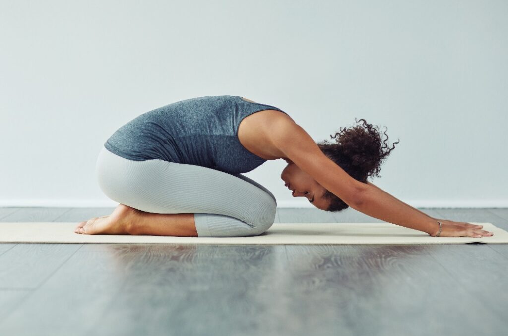 Yoga, Kind-Pose und Frau Stretching auf Matte für Wellness, Training und Fitness im Fitnessstudio. Gesunder Körper, Meditation und weibliche Person, die Pilates-Übungen für Gleichgewicht, Flexibilität und Wohlbefinden macht