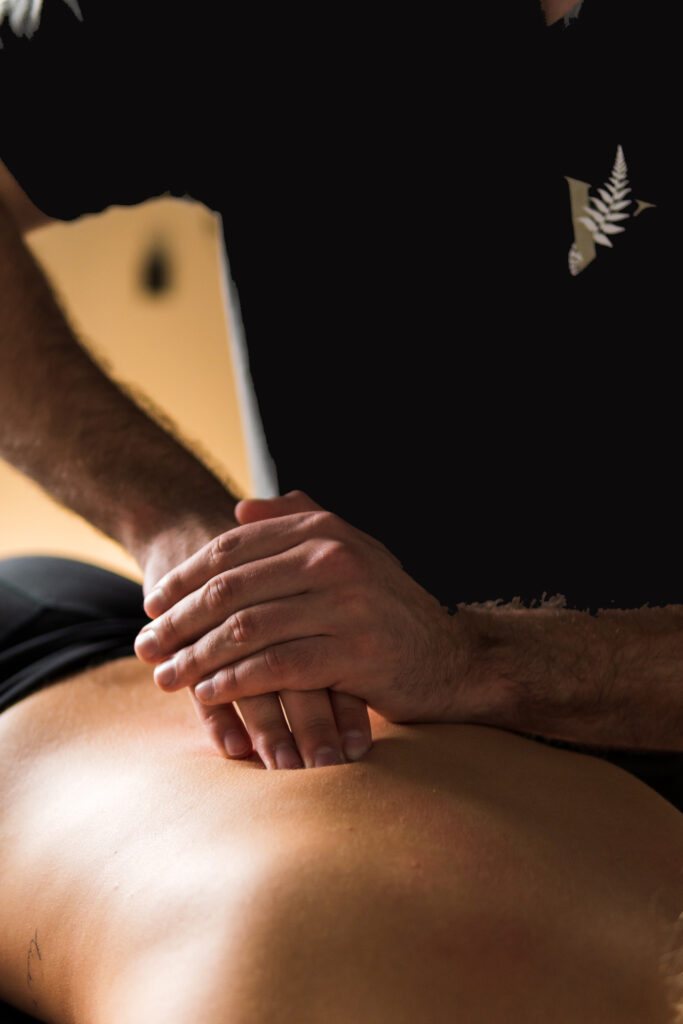 Ein Mann mit kurzen Haaren führt konzentriert eine Massage auf einem Rücken aus