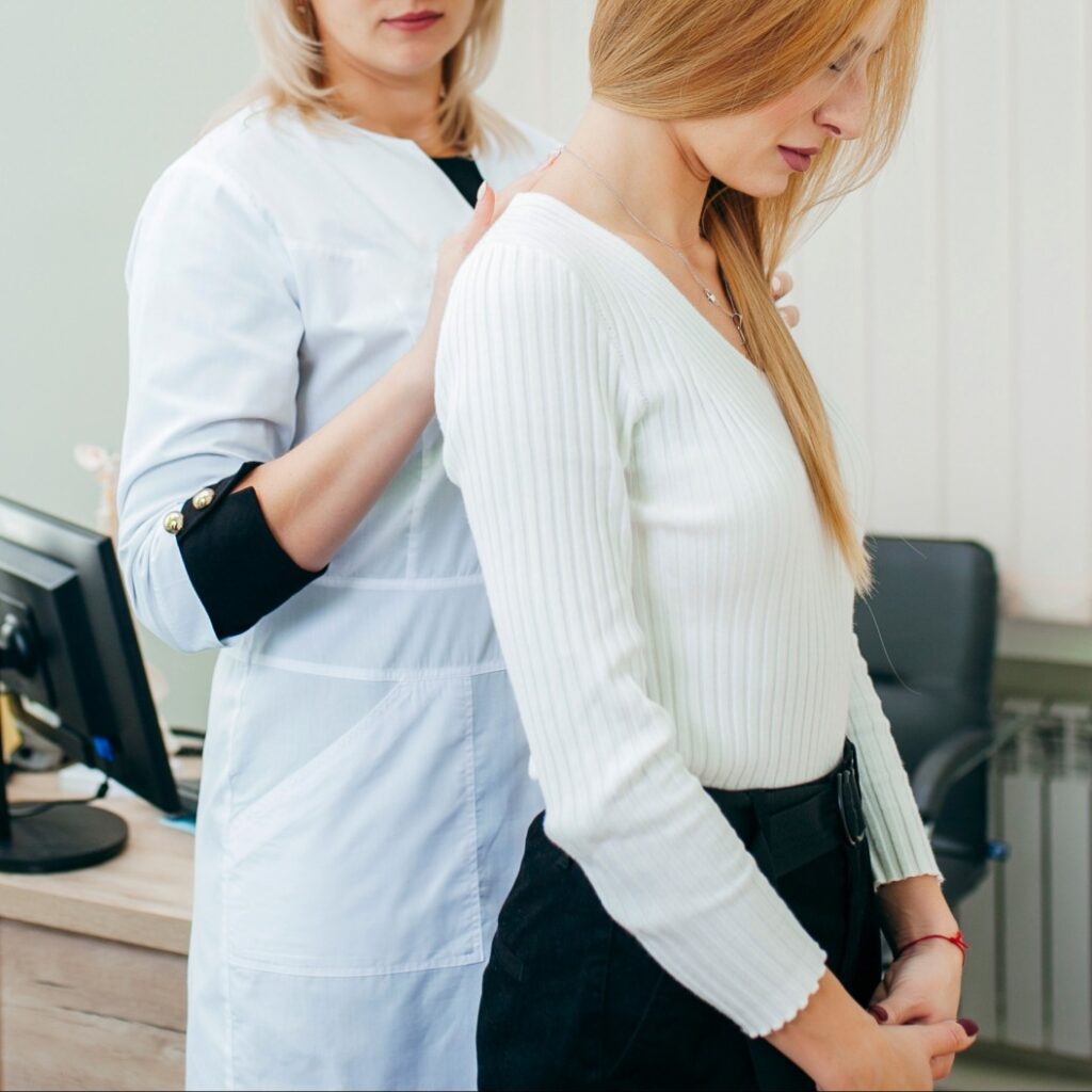 Nahaufnahme: Eine Neurologin untersucht in einer Arztpraxis die Halswirbelsäule einer Patientin. Neurologische körperliche Untersuchung. Osteopathie, Chiropraktik, Physiotherapie